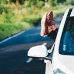 Woman hanging feet with shoes out of car window