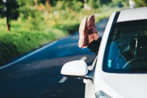 Woman hanging feet with shoes out of car window