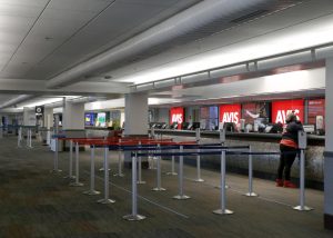 People waiting in a line at a car rental counter, symbolizing the moment travelers decide on purchasing rental insurance.