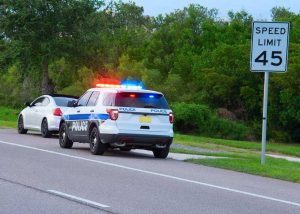 A man getting pulled over by a cop for speeding and is wondering his speeding ticket will show up on insurance.