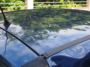 A close-up view of a car hood with numerous small dents, symbolizing vehicle damage caused by a hailstorm that may be covered by insurance.