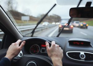 A close-up of a driver's hands gripping a car's steering wheel, representing the common act of driving that can be subject to bizarre traffic laws.