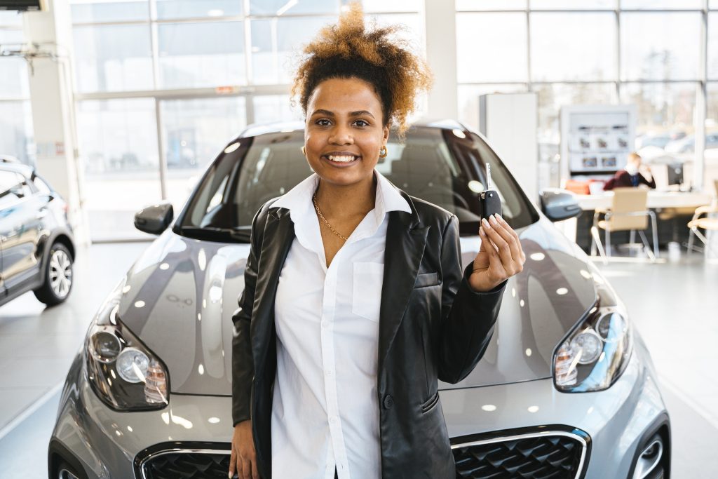 woman with keys for a new car in showroom