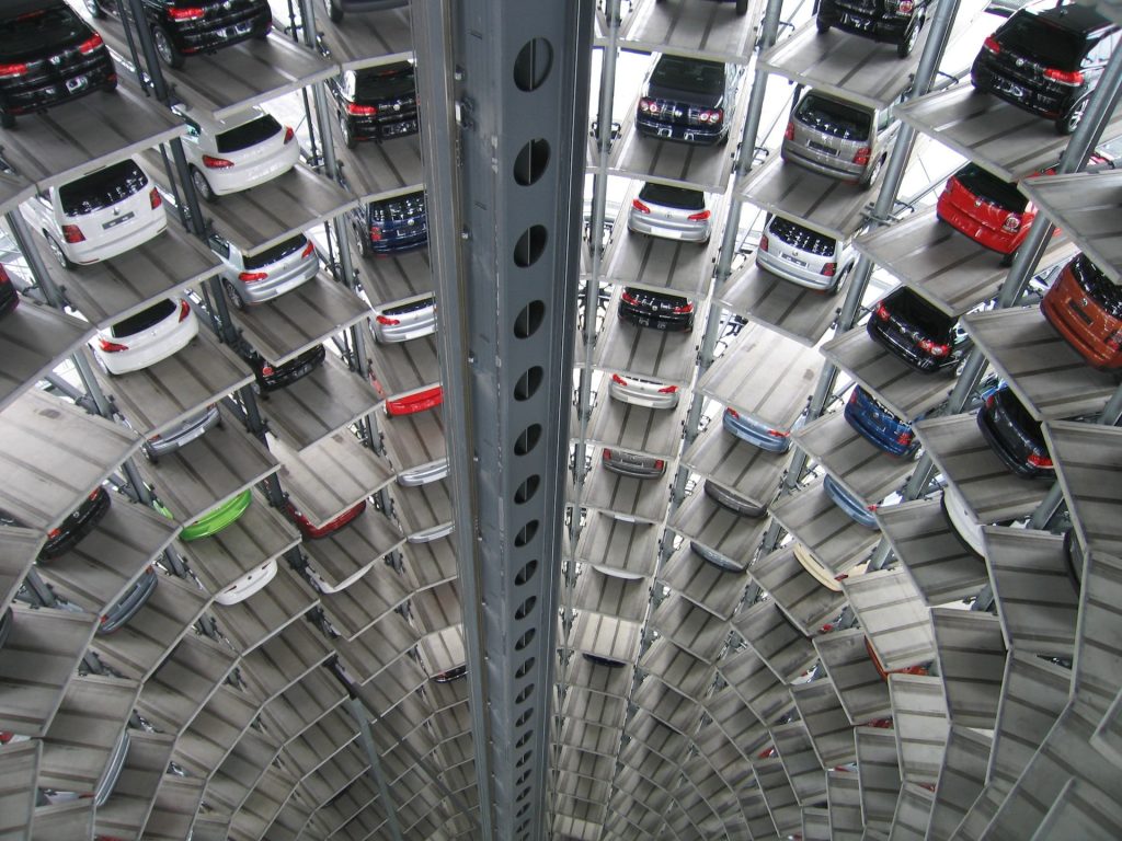 many new cars parked on dozens of levels in a new car tower