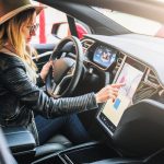 woman wearing hat using touch screen in car