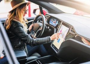 A woman operating a car's modern touchscreen display, symbolizing the evolution of in-vehicle technology and automation.