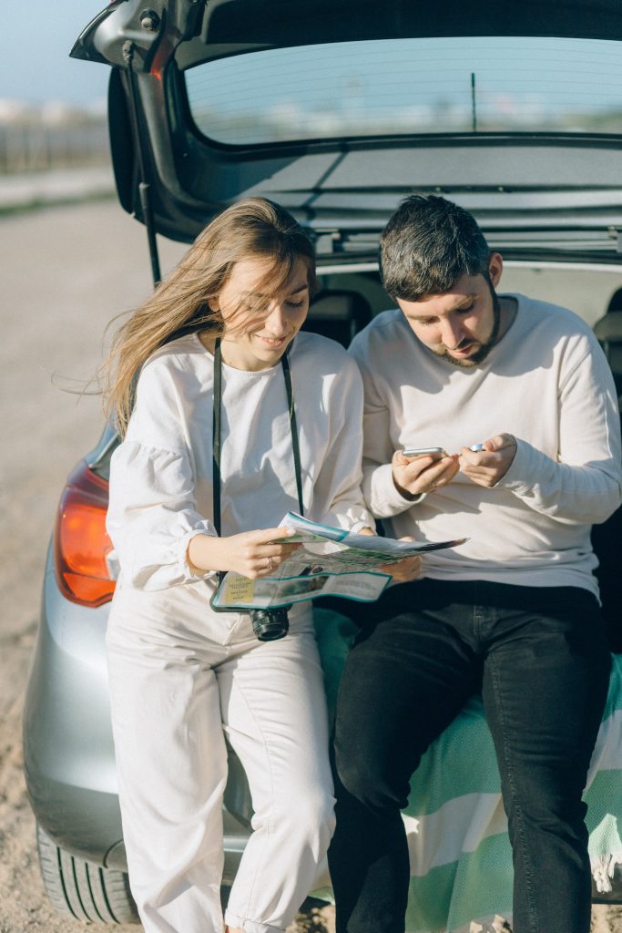 couple sitting at back of car reviewing options
