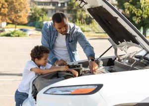 A father and son working on a car engine together, symbolizing a simple DIY car repair that can be done at home.