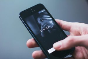 A person's hand using a ride-sharing app on a smartphone, with a price increase notification, symbolizing the concept of surge pricing.