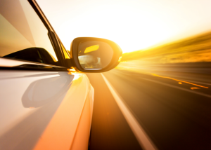 A view from inside a car showing the side view mirror and the road ahead, representing the experience of driving one of the bestselling vehicles.