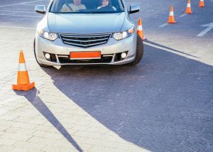 A car maneuvering through cones in a driving course, representing a new driver learning to drive with a learner's permit.