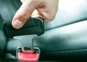 A close-up of a person's hand buckling a seatbelt, symbolizing a simple action that can save lives and prevents a seat belt ticket.