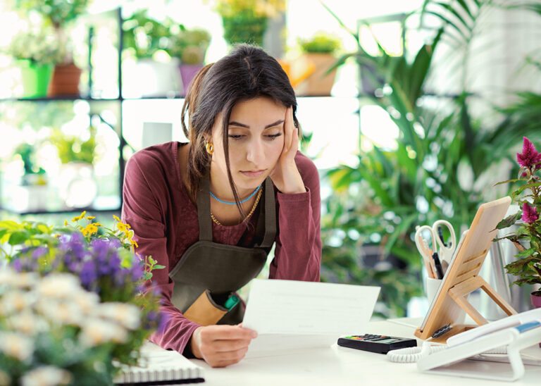 A worried, sad-looking business owner reading a letter indicating rising insurance premiums, symbolizing the financial challenges faced by small businesses.